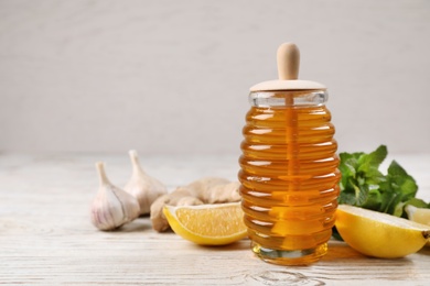Photo of Jar of honey, ginger, garlic, mint and lemon on wooden table, space for text. Cough remedies