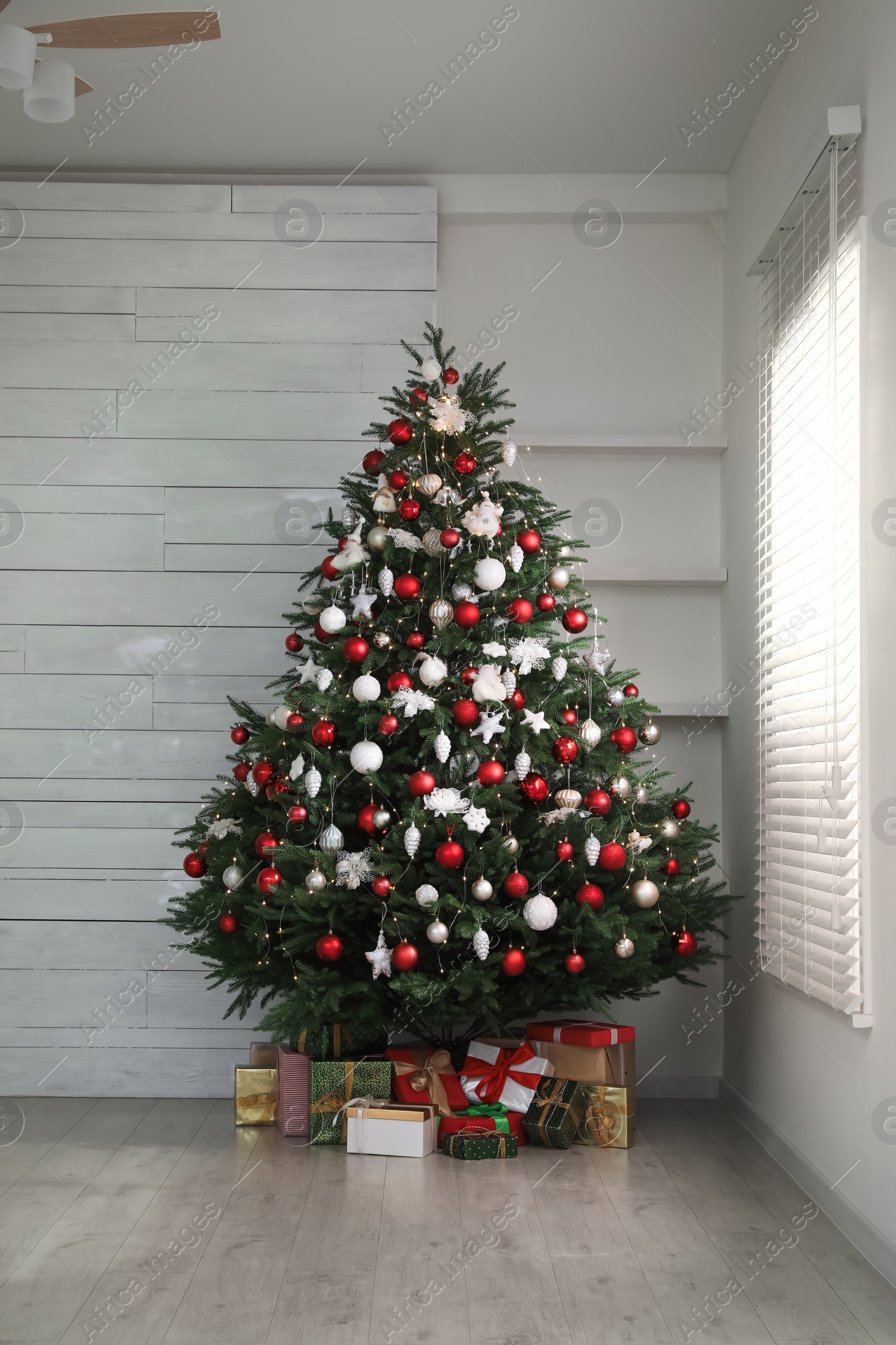 Photo of Beautifully decorated Christmas tree and gifts near window indoors