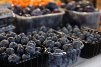 Fresh blueberries and plums on counter at market, closeup