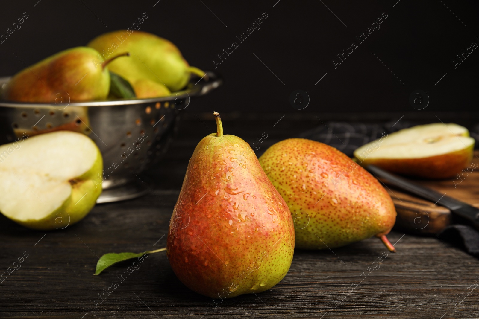 Photo of Ripe juicy pears on dark wooden table against black background