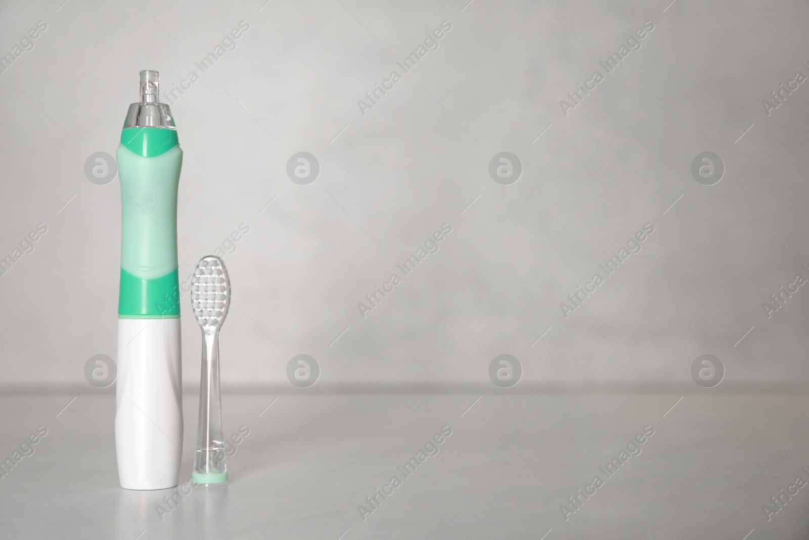 Photo of Electric toothbrush on light background, space for text