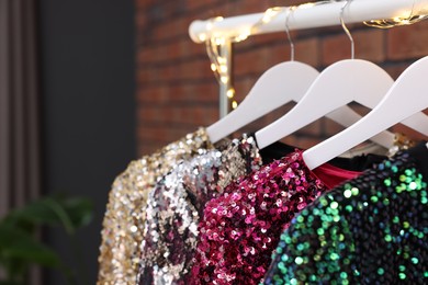 Photo of Collection of different beautiful women's party dresses on hangers indoors, closeup and space for text. Stylish trendy clothes for high school prom