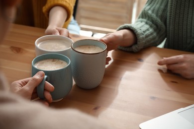 Photo of Women with cups of coffee at table in cafe, closeup