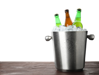 Photo of Metal bucket with bottles of beer and ice cubes on wooden table against white background. Space for text