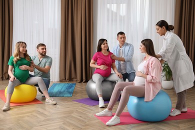 Pregnant women with men and doctor at courses for expectant parents indoors