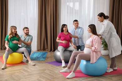 Photo of Pregnant women with men and doctor at courses for expectant parents indoors