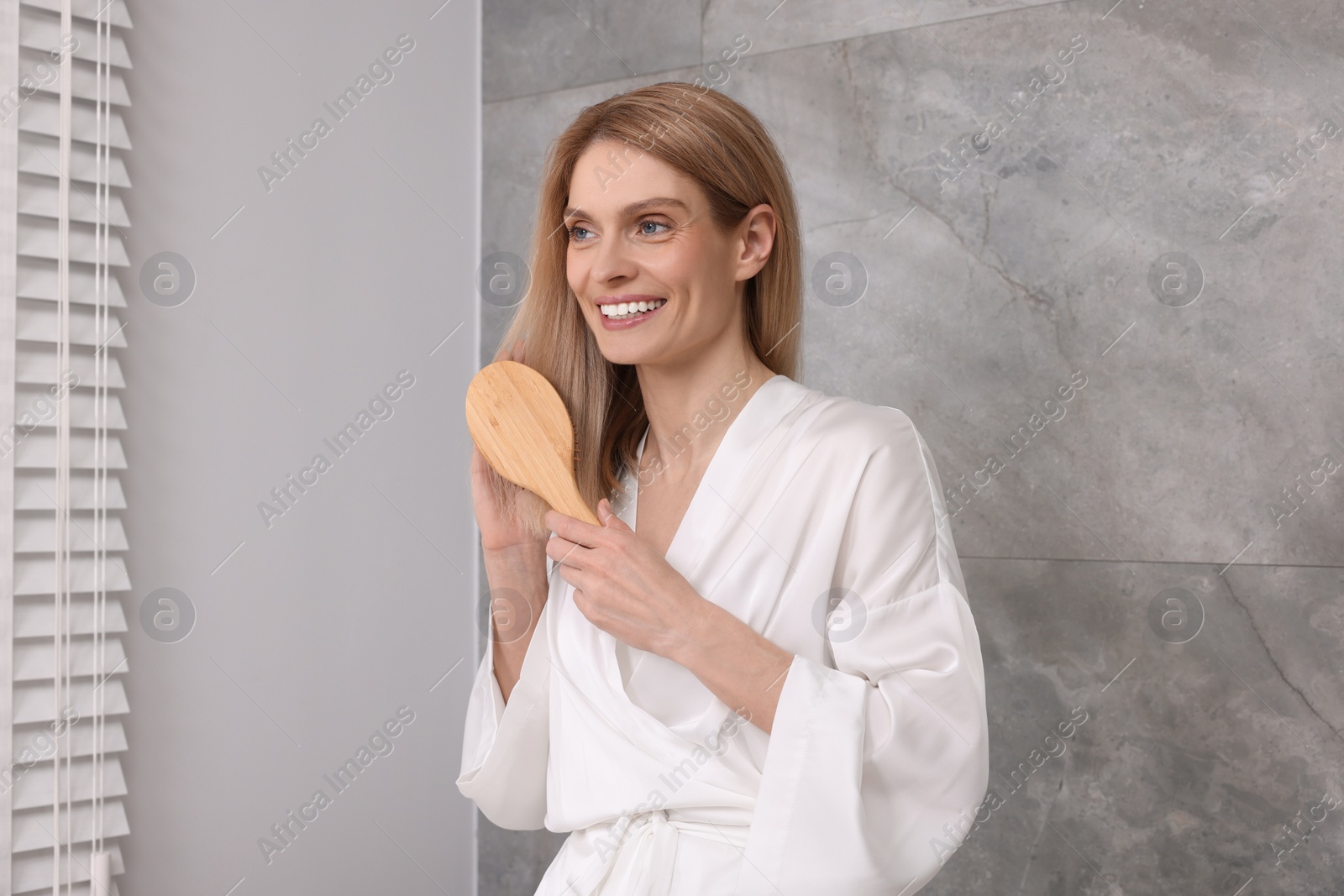 Photo of Beautiful woman brushing her hair in bathroom