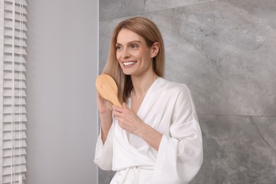 Beautiful woman brushing her hair in bathroom