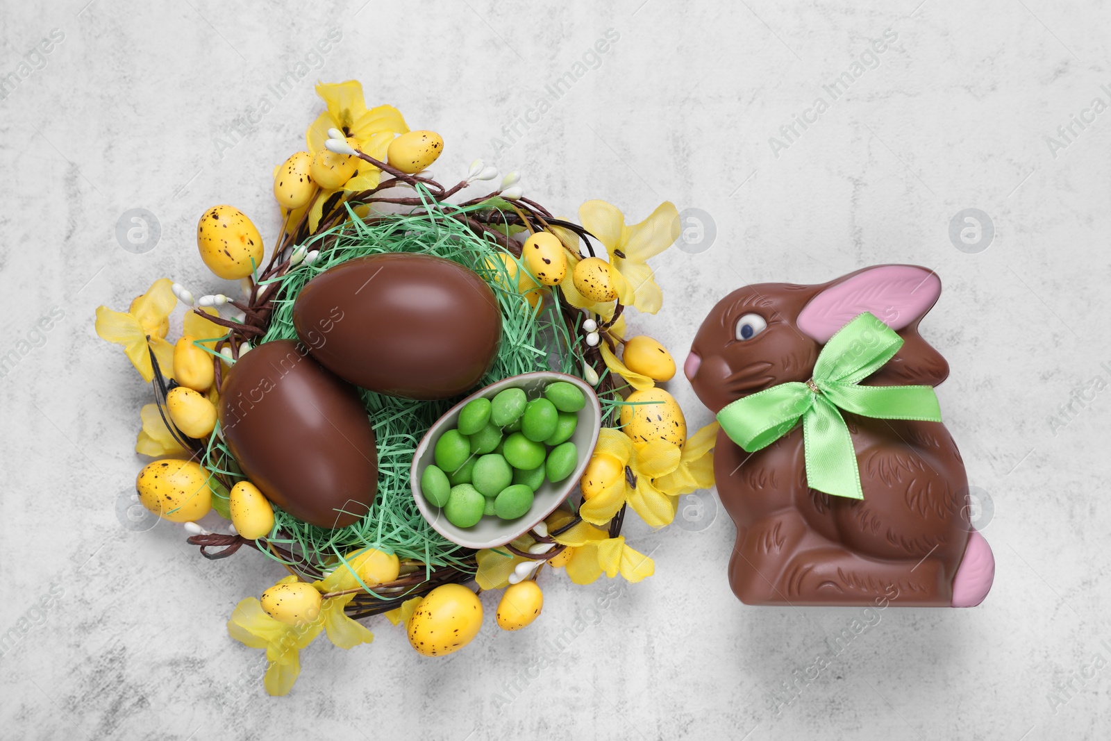 Photo of Flat lay composition with chocolate Easter bunny, eggs and candies on white textured table