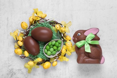 Photo of Flat lay composition with chocolate Easter bunny, eggs and candies on white textured table
