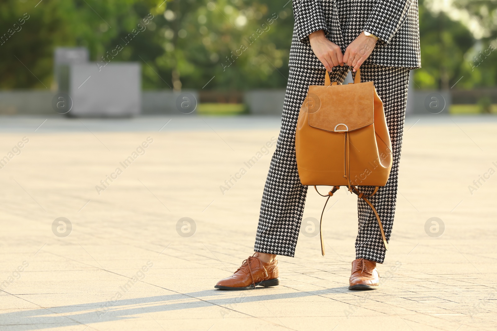 Photo of Young woman with stylish backpack on city street, closeup. Space for text