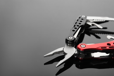 Photo of Compact portable multitool on grey table, closeup. Space for text