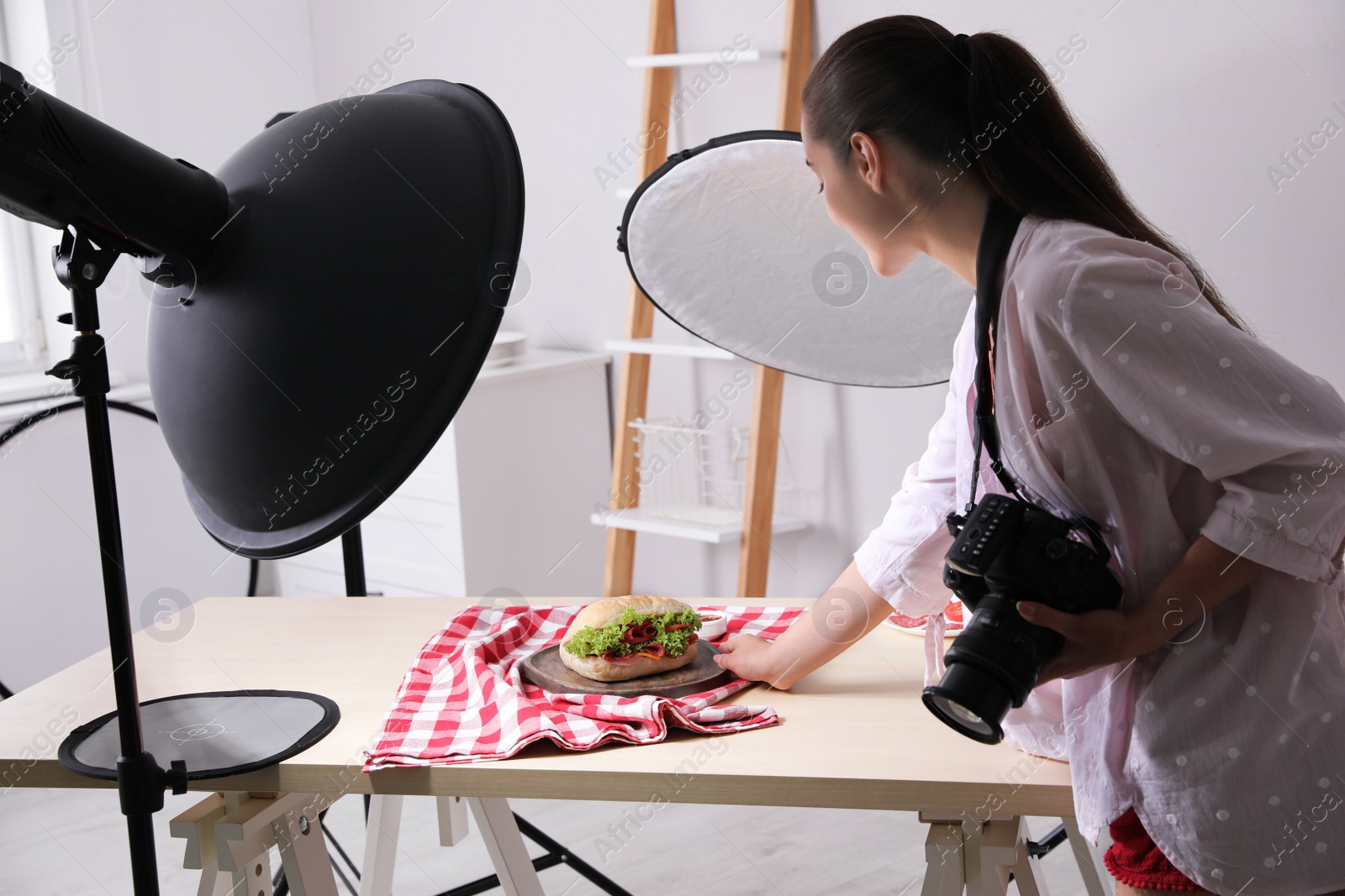 Photo of Young woman creating composition with sandwich in studio. Food photography
