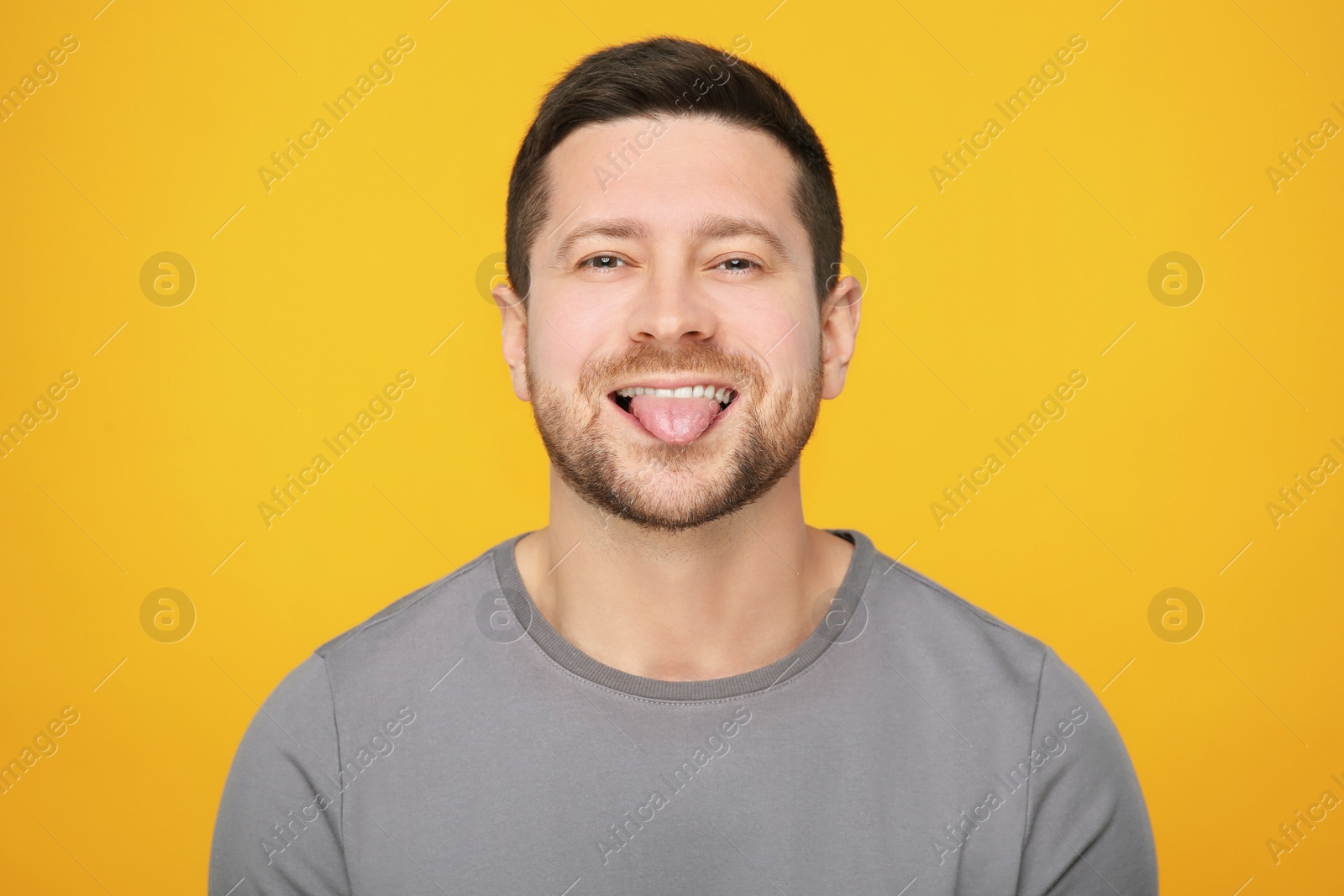 Photo of Happy man showing his tongue on orange background