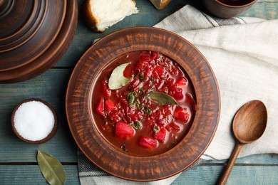 Stylish brown clay plate with Ukrainian borsch served  on wooden table, flat lay
