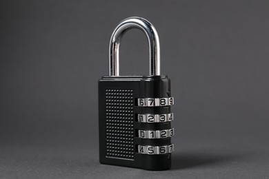 Photo of One steel combination padlock on dark grey background, closeup