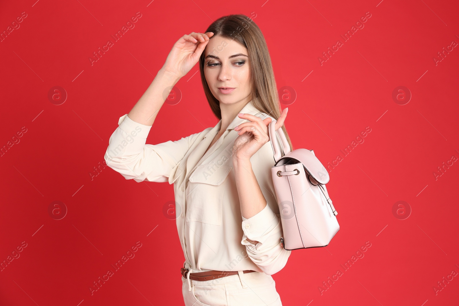 Photo of Beautiful young woman in casual outfit with stylish bag on red background