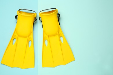 Photo of Pair of yellow flippers on turquoise background, flat lay