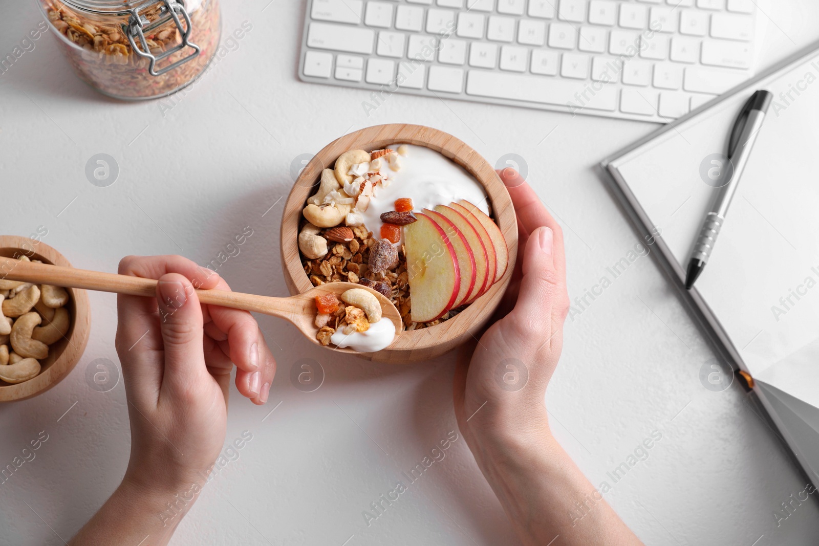 Photo of Woman eating tasty granola at workplace, top view