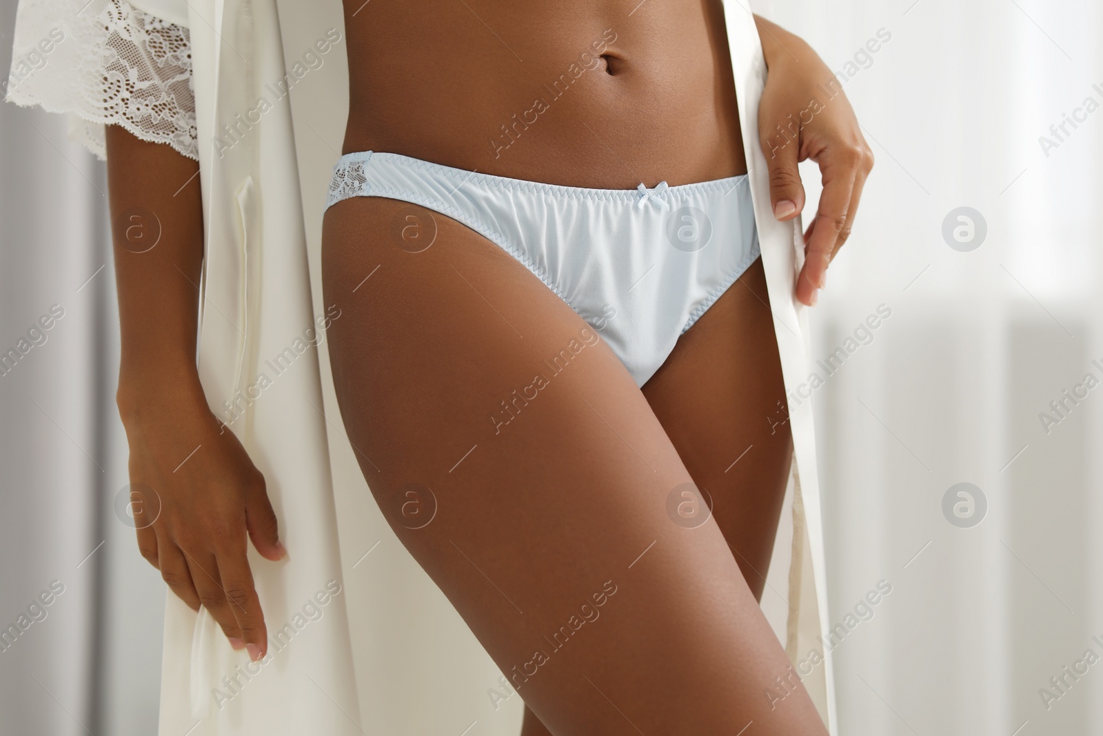 Photo of Woman in elegant light blue underwear and robe indoors, closeup