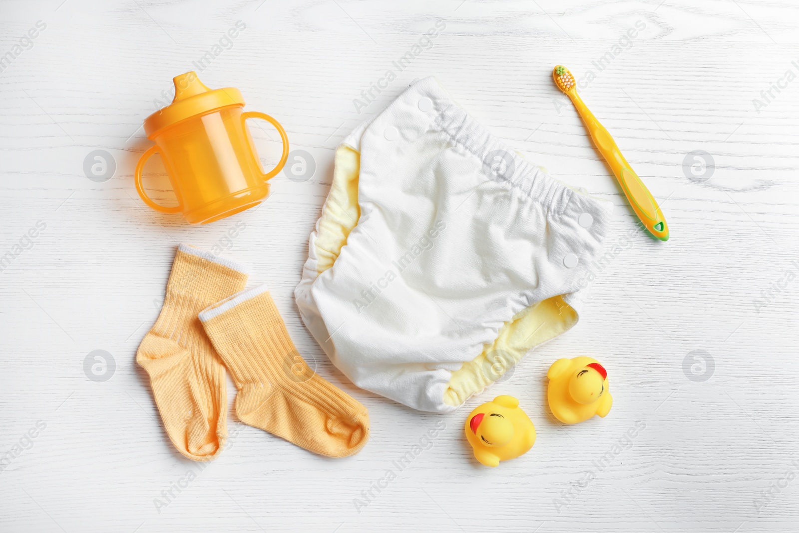 Photo of Flat lay composition with cute clothes on white wooden background. Baby accessories