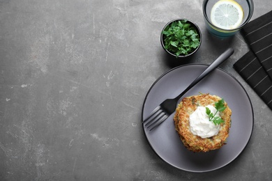 Photo of Delicious zucchini fritters served on grey table, flat lay. Space for text