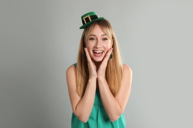 Happy woman in St Patrick's Day outfit on light grey background