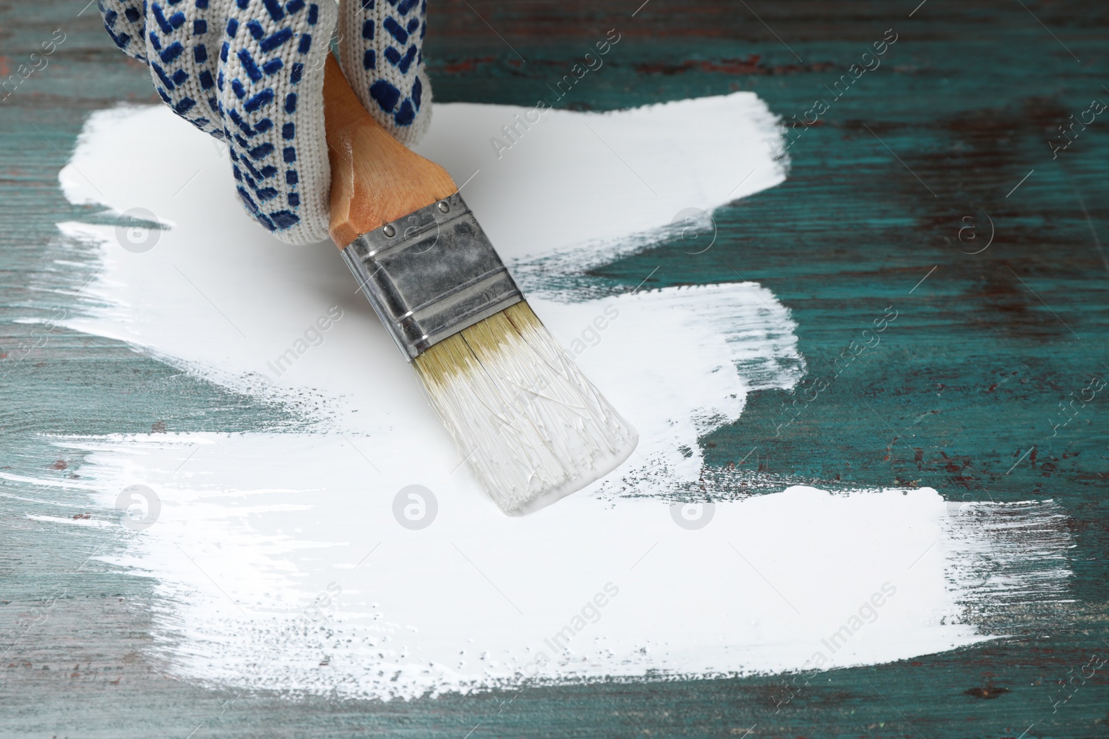 Photo of Person painting teal wooden surface white, closeup