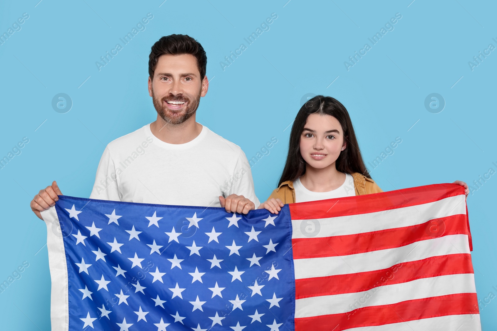 Photo of 4th of July - Independence Day of USA. Happy man and his daughter with American flag on light blue background