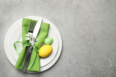 Festive Easter table setting with floral decor on grey background, top view. Space for text