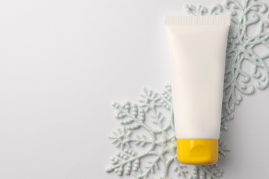 Photo of Winter skin care. Hand cream and decorative snowflakes on white background, top view. Space for text