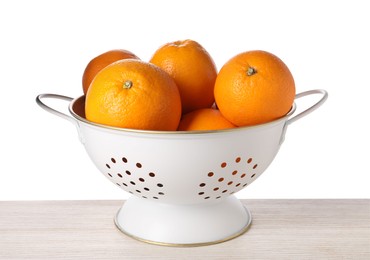 Photo of Fresh oranges in colander on wooden table against white background