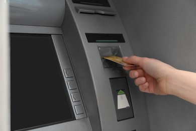 Photo of Woman inserting credit card into cash machine outdoors, closeup