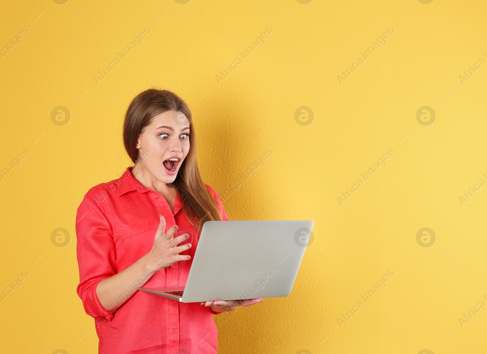 Photo of Emotional young woman with laptop celebrating victory on color background. Space for text