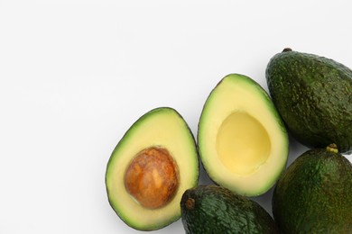 Tasty whole and cut avocados on white background, flat lay. Space for text