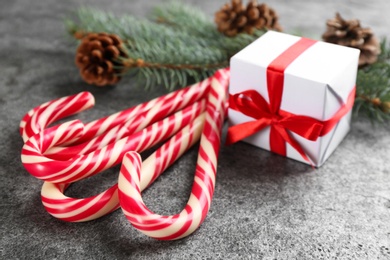 Photo of Christmas candy canes and gift box on grey table, closeup