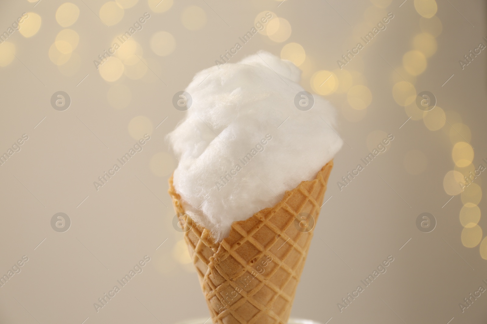 Photo of Sweet cotton candy in waffle cone against blurred lights, closeup