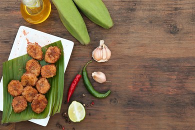 Delicious fried bananas, fresh fruits and different peppers on wooden table, flat lay. Space for text