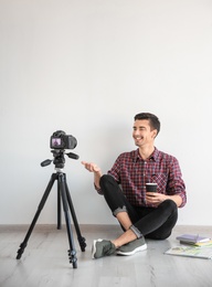 Young blogger recording video near light wall