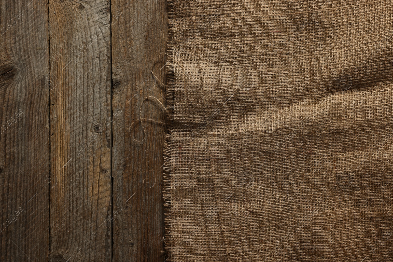 Photo of Burlap fabric on wooden table, top view. Space for text
