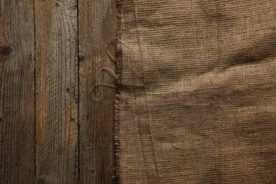 Burlap fabric on wooden table, top view. Space for text