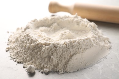 Pile of flour and rolling pin on grey marble table, closeup