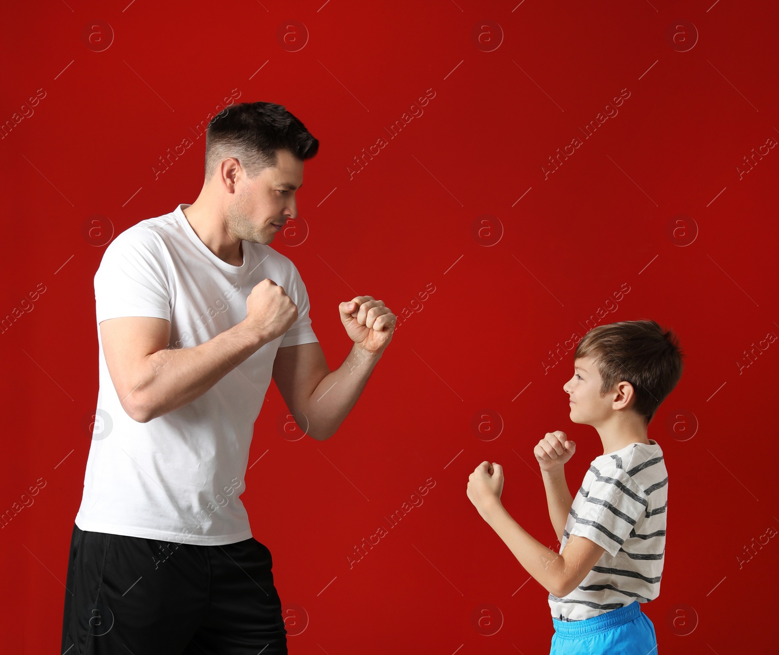 Photo of Portrait of dad and his son boxing on color background