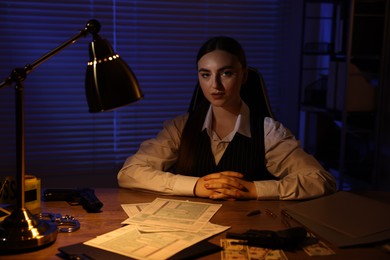 Professional detective working at table in office at night