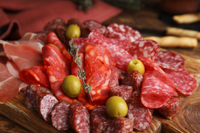 Tasty prosciutto with other delicacies served on wooden table, closeup