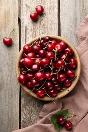 Fresh ripe cherries and towel on wooden table, flat lay
