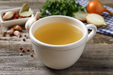 Hot delicious bouillon in cup on wooden table, closeup