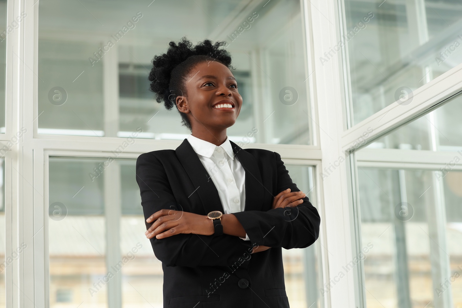 Photo of Happy woman with crossed arms in office, low angle view. Lawyer, businesswoman, accountant or manager