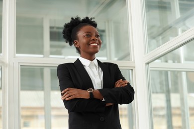 Happy woman with crossed arms in office, low angle view. Lawyer, businesswoman, accountant or manager