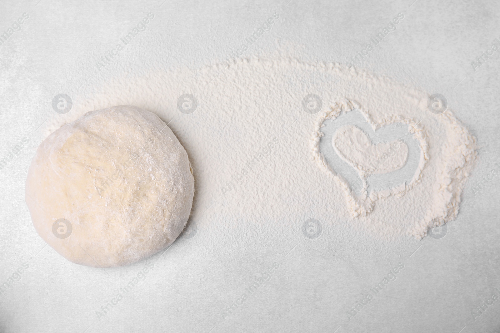 Photo of Heart made of flour and dough on light grey table, top view